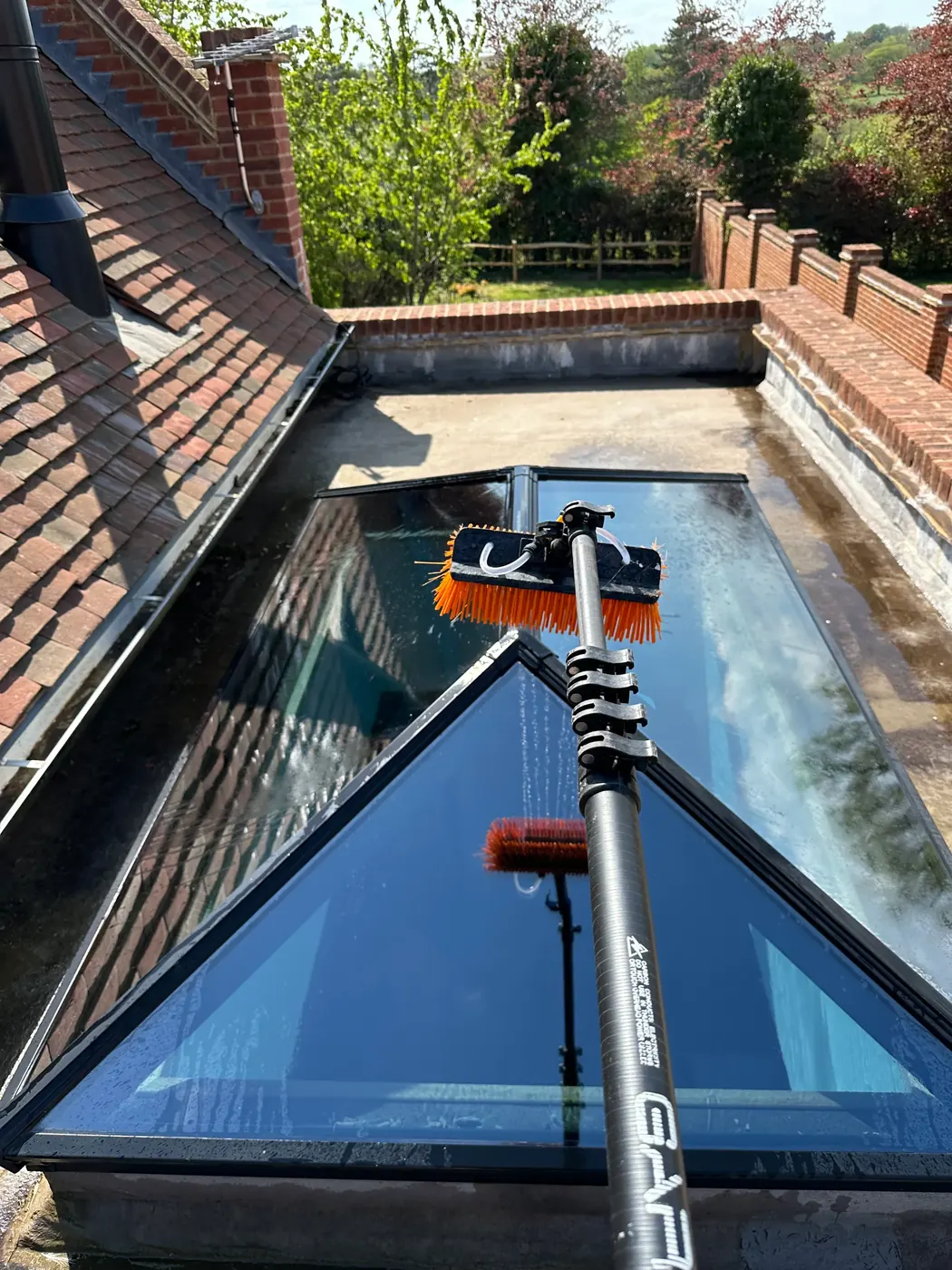 Water-fed pole brush cleaning a glass conservatory roof and skylight