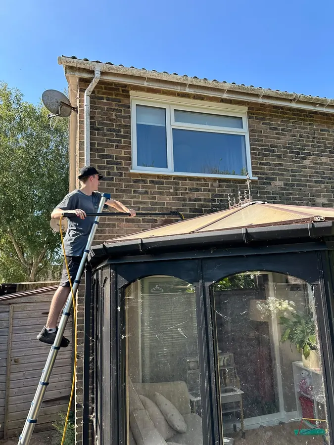 A team member clearing debris from a conservatory roof