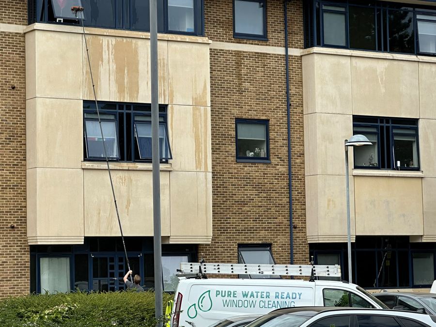 Water-fed pole reaching upper-floor windows on a commercial building